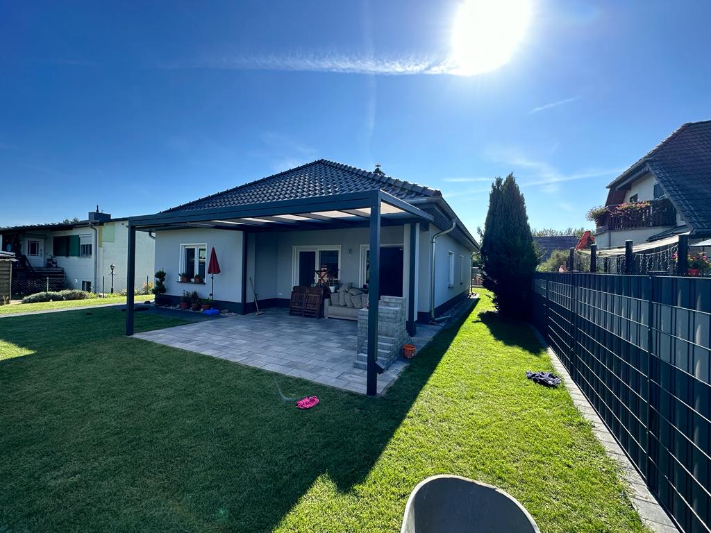 Die ganze Terrassenüberdachung im Garten von der Ecke. Anderes Haus und Bäume sind auch zu sehen